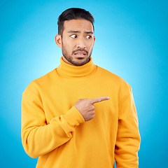 Image showing Wtf, surprise and asian man hand pointing in studio for menu, questions and how to steps on blue background. Omg, doubt and male face with finger show feedback, schedule or presentation with anxiety