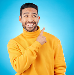 Image showing Asian man, smile and hand pointing to studio for news, deal and discount or how to guide on blue background. Happy, choice and male show timeline, checklist or direction, coming soon or sign up info