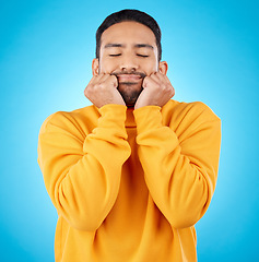 Image showing Man, shy and touching cheeks in studio isolated on a blue background. Peace, calm and person in love, relax for zen and meditation, content and satisfied with eyes closed, hands on face and wellness