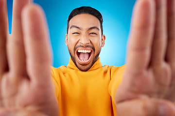 Image showing Selfie, excited and portrait of a man in studio with hands and shout emoji. Face of asian male or fashion model on blue background with surprise and fun energy for social media profile picture update