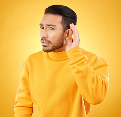 Image showing Whisper, gossip and asian man with hand on ear in studio for speak up body language on yellow background. Secret, listen and male person with hush, news or confidential coming soon promo announcement