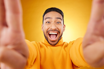 Image showing Funny, portrait and selfie of excited man in studio isolated on a yellow background. Face, smile and Asian person taking profile picture for happy memory, laughing and photography on social media