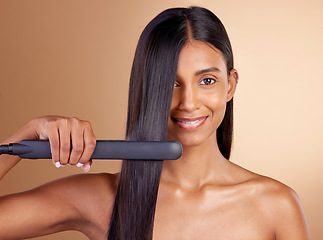 Image showing Portrait, hair and straightener with a model woman in studio on a beige background for beauty or style. Face, smile and haircare with happy young person using a flat iron appliance for natural care