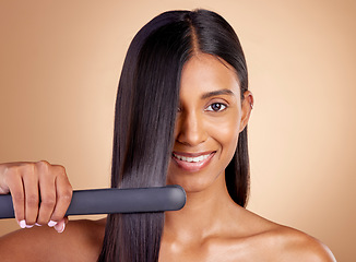 Image showing Portrait, hair and flat iron with a woman in studio on a beige background for beauty or style. Face, smile and haircare with happy young female model using a straightener appliance for natural care