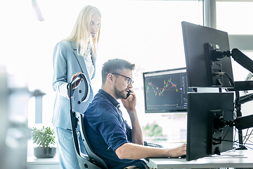 Image showing Stock broker business team trading online watching charts and data analyses on multiple computer screens in modern corporate work station office.