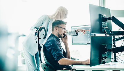 Image showing Stock broker business team trading online watching charts and data analyses on multiple computer screens in modern corporate work station office.