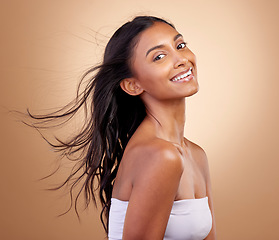 Image showing Salon, hairstyle and beauty with indian woman or shine in brown studio background. Haircare, shine and happy face with wind or growth for glow with keratin treatment in mockup or natural cosmetics.