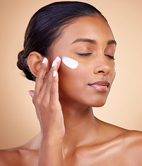 Image showing Face, cream and woman with eyes closed for skincare cosmetics, dermatology or aesthetic makeup on studio background. Indian female model, lotion and facial sunscreen for clean beauty, glow and shine