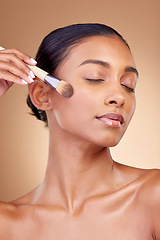 Image showing Beauty, makeup and product with woman and brush in studio for facial, foundation and self care. Cosmetics, spa and tools with face of model on brown background for glow, skincare and dermatology