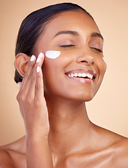 Image showing Woman, happy skincare and cream for facial beauty, apply lotion and dermatology or cosmetics. Skin care product, face and young person or model sunscreen or moisturizer on a brown studio background