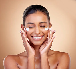 Image showing Facial cream, skincare smile of woman for aesthetic shine, cosmetics or clean dermatology on studio background. Happy indian female model, face lotion or sunscreen product for healthy beauty glow