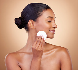 Image showing Woman, cotton pad and skincare of face cosmetics for aesthetic wellness on studio background. Happy indian female model, clean beauty and facial dermatology product for makeup removal, shine and glow