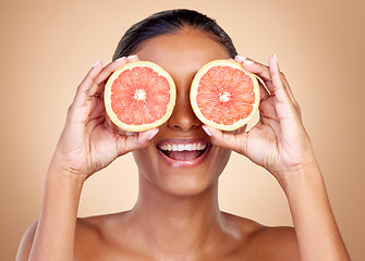 Image showing Grapefruit, beauty and eyes of happy woman in studio, vitamin c nutrition or natural glow. Face of female model, healthy skincare or smile with citrus fruits, eco dermatology or sustainable cosmetics