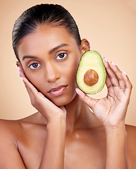 Image showing Avocado, beauty and woman in portrait for healthy face and natural skincare on studio brown background. Young indian person or model with green fruits, vitamin c benefits and dermatology or cosmetics