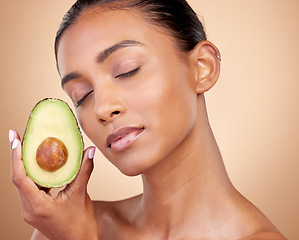 Image showing Avocado, beauty and woman in studio, background and eyes closed for aesthetic glow. Face of indian model, natural skincare and fruit for sustainable cosmetics, vegan dermatology and facial benefits