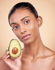 Image showing Avocado, skincare and woman in portrait for healthy face and natural beauty on studio brown background. Young indian person or model with green fruits, vitamin c benefits and dermatology or cosmetics