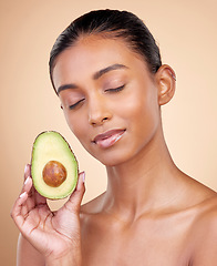 Image showing Avocado, facial beauty and woman in studio, background and omega 3 for aesthetic wellness. Face of calm indian female model, natural skincare and fruit for sustainable cosmetics, healthy food or glow