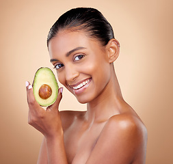 Image showing Avocado, beauty and portrait of happy woman in studio, background and aesthetic glow. Face of indian model, natural skincare and fruit for sustainable cosmetics, vegan dermatology and facial benefits