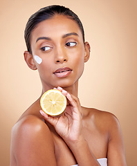 Image showing Woman, thinking and cream with lemon for skincare, cosmetics and natural beauty product or vitamin c benefits. Facial sunscreen of young person with fruits for dermatology on studio, brown background