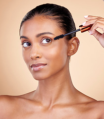 Image showing Beauty, makeup and mascara with face of woman in studio for cosmetics, eyelashes and glamour. Self care, application and tools with female model on brown background for product, volume and glow