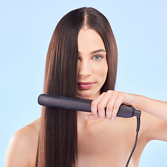 Image showing Portrait, woman and hair iron for beauty in studio, cosmetic treatment or shine on blue background. Face of female model, haircare and heating equipment of electric tools, smooth texture or aesthetic