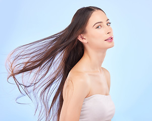 Image showing Portrait, hair and wind with a model woman in studio on a blue background for skincare or keratin treatment. Spa, salon and haircare with a young female person posing for beauty or shampoo promotion