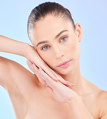 Image showing Face on hands, beauty and woman, natural and cosmetics with skincare isolated on blue background. Female model, healthy glow and clean skin, dermatology and portrait with spa facial in a studio