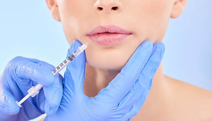 Image showing Injection, woman and lips with plastic surgeon for beauty with botox or hands in studio with blue background. Face, syringe and doctor for injecting mouth with collagen or filler and implants.