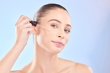 Image showing Woman, portrait and oil serum for face, aesthetic skincare and dermatology on blue background. Female model, facial cosmetics and dropper of hyaluronic acid, liquid collagen and beauty glow in studio