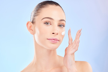 Image showing Face, skincare and woman with sunscreen in studio isolated on a blue background. Portrait, dermatology and serious model with cream, beauty cosmetic or moisturizer for health, aesthetic or wellness