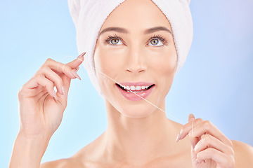 Image showing Happy woman, face and thinking with dental floss for teeth cleaning or hygiene against a blue studio background. Female person in wonder, flossing or self love for tooth whitening, oral and gum care