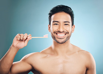 Image showing Dental, portrait and Asian man with a toothbrush, oral hygiene and wellness against a blue studio background. Face, male person and happy model teeth cleaning product, toothpaste and fresh breath