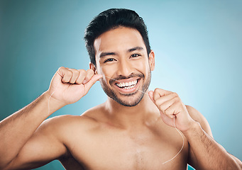 Image showing Wellness, teeth and dental floss of a man portrait with cleaning and dental health in a studio. Face, blue background and healthy male person with flossing for mouth hygiene and healthcare with smile