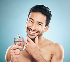 Image showing Portrait, perfume and man with cologne, self care and grooming against a blue studio background. Face, male person and model with wellness, luxury and aesthetic with skincare and fragrance bottle