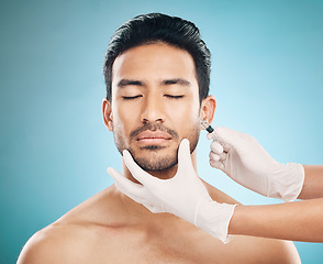 Image showing Face, hands and transformation with a plastic surgery man in studio on a blue background for beauty enhancement. Aesthetic, botox or prp with a young male patient eyes closed in a clinic for skincare