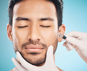 Image showing Face, hands and change with a plastic surgery man in studio on a blue background for beauty enhancement. Aesthetic, botox or prp with a young male patient eyes closed in a clinic for skincare closeup