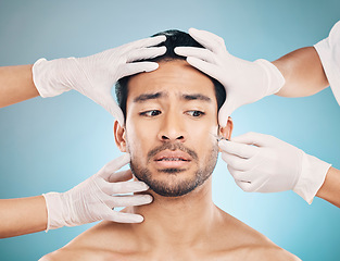 Image showing Face, hands and plastic surgery with a worried man in studio on a blue background for beauty enhancement. Aesthetic, botox or change with a young male patient looking nervous in a clinic for skincare