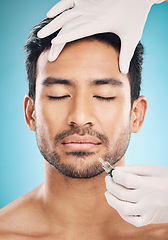 Image showing Face, hands and botox with a plastic surgery man in studio on a blue background for beauty enhancement. Aesthetic, transformation or change with a young patient eyes closed in a clinic for skincare