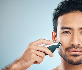 Image showing Portrait, shaving and electric razor with a man in studio on a blue background for personal hygiene or grooming. Face, wellness and cosmetics with a young male in the bathroom for hair removal