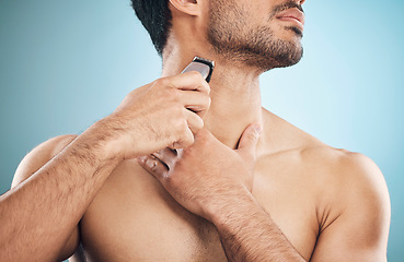 Image showing Hands, shaving and electric razor with a man in studio on a blue background for personal hygiene or grooming. Beauty, wellness and cosmetics with a young male in the bathroom for hair removal