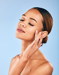 Image showing Woman, touch face and beauty, makeup and skincare with shine and manicure isolated on blue background. Female model, hand with dermatology and facial, healthy skin glow and cosmetic care in a studio