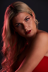 Image showing Portrait, luxury and makeup with a model woman in studio on a dark background in red lighting for desire. Face, beauty or skincare with a young female person posing for natural feminine confidence