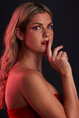 Image showing Portrait, beauty and sensual with a model woman in studio on a dark background in red lighting for desire. Face, makeup or lipstick with a young female person posing for natural feminine confidence