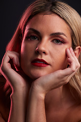 Image showing Portrait, skincare and luxury with a model woman in studio on a dark background in red lighting for desire. Face, beauty and makeup with a young female person posing for natural feminine confidence