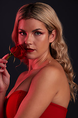 Image showing Portrait, beauty and rose with a model woman in studio on a dark background for valentines day. Face, skincare or flower with a young female person posing in red for natural feminine confidence