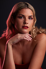 Image showing Portrait, face and beauty with a woman in studio on a dark background in red lighting for desire. Skincare, makeup or cosmetics with a young female model posing for natural feminine confidence