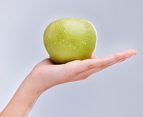 Image showing Vegan, hand and apple with water drops, nutrition and clean against a grey studio background. Zoom, fingers and person with a fruit in a palm, detox and snack for diet with self care and wellness