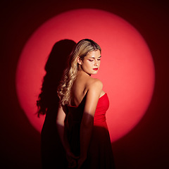 Image showing Beauty, spotlight and red with a model woman in studio on a dark background for classy elegance or style. Fashion, aesthetic and luxury with a confident young female person standing in a dress