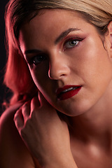 Image showing Portrait, beauty and makeup with a model woman in studio on a dark background in red lighting for desire. Face, skincare or cosmetics with a young female person posing for natural feminine confidence