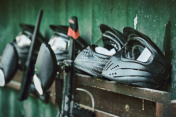 Image showing Paintball, helmet and guns on rack at battle station of sports gear waiting for players, competition or war. Paint balling sportswear or stationary equipment ready for serious game, fight or warfare